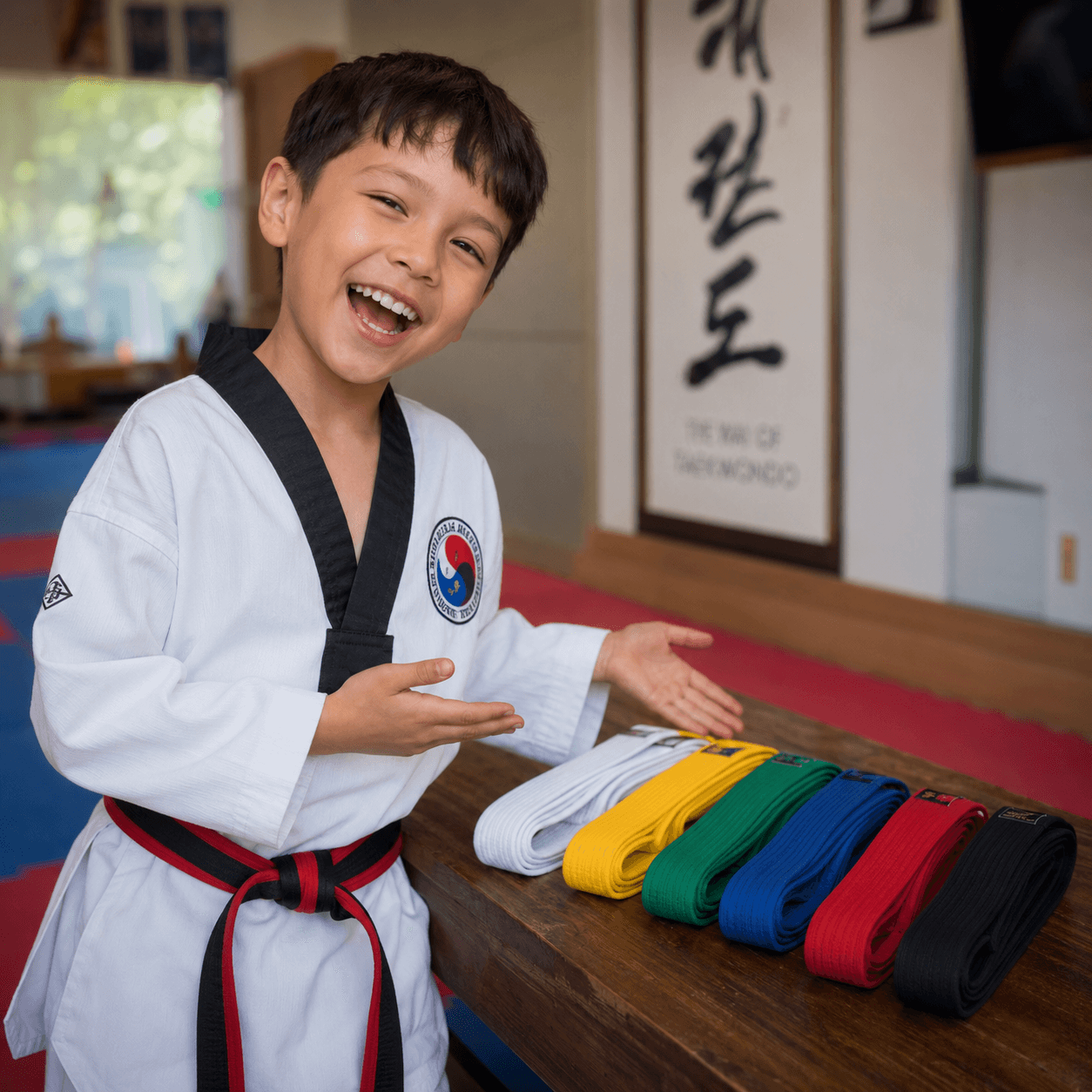 A young taekwondo student celebrating a belt promotion.