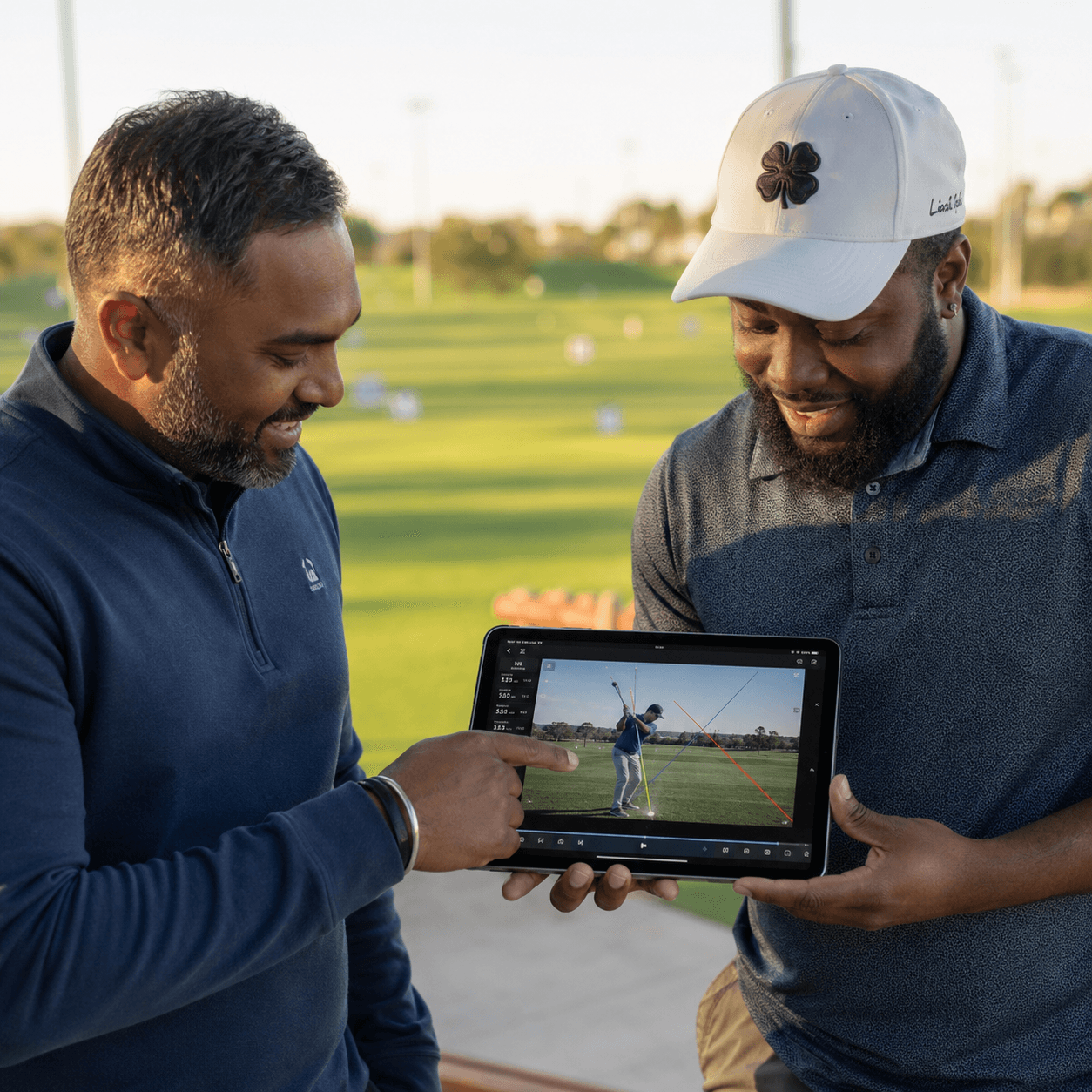 A golf coach reviewing a student’s swing on a tablet.