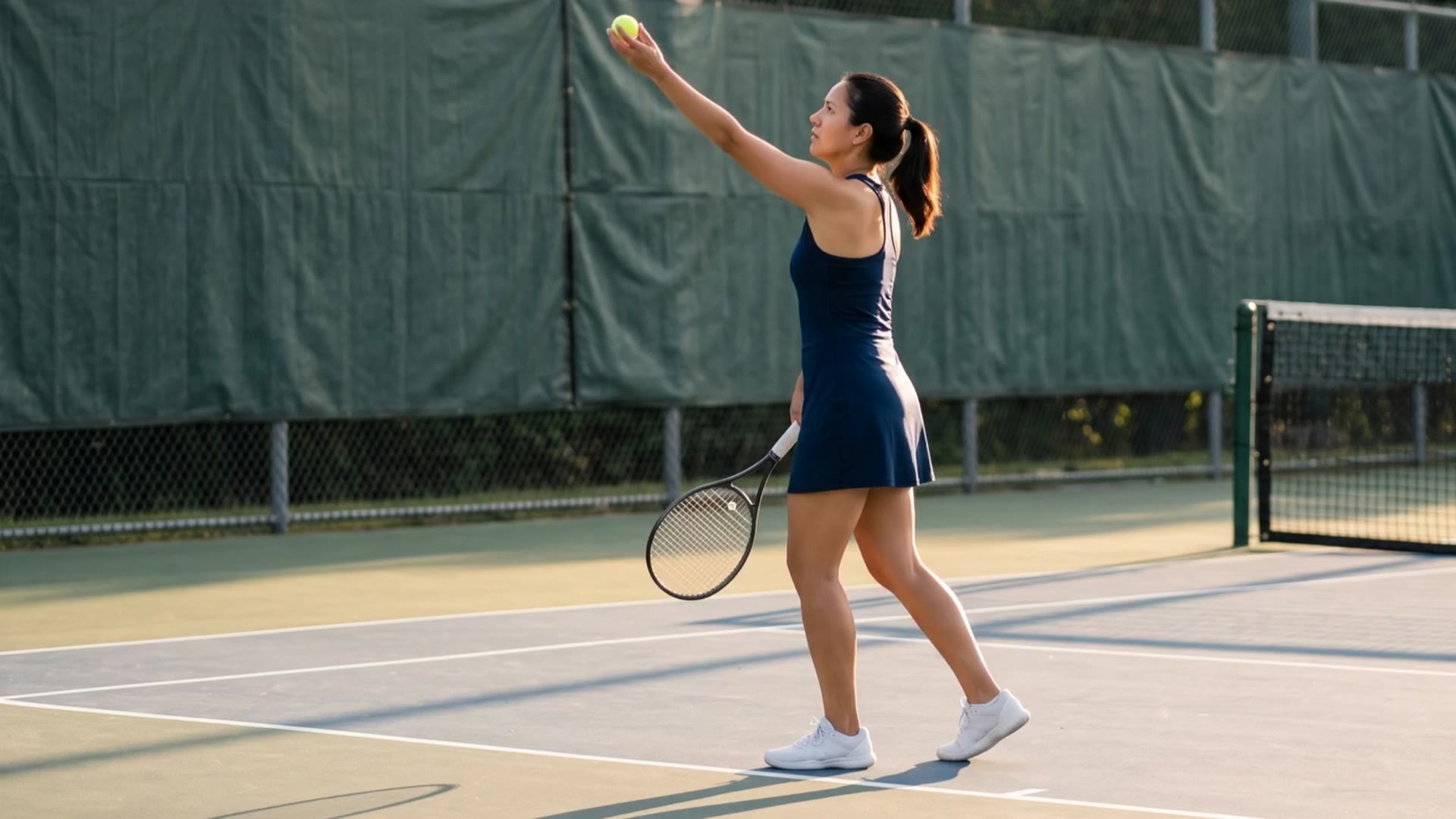 A tennis player preparing to serve at the baseline, filmed from a lesson camera.